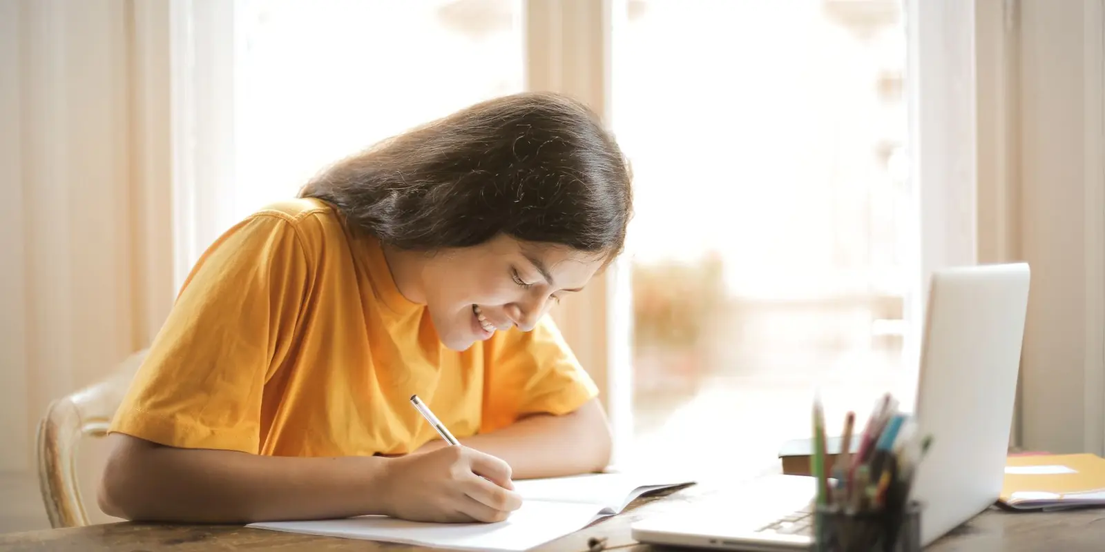 Pelajar belajar di meja dengan laptop terbuka