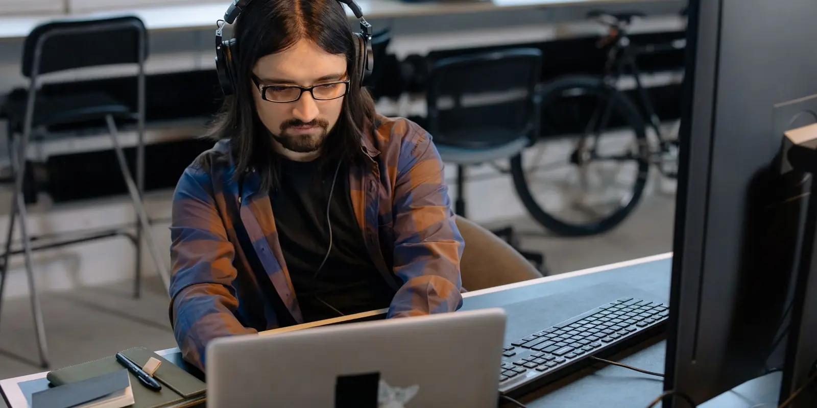 Programmer pakai headphone kerja di depan laptop
