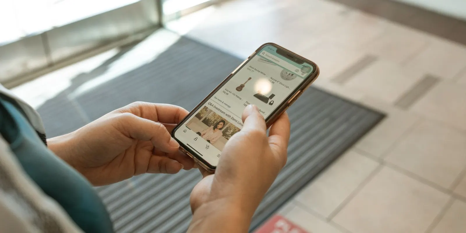 Tangan pegang HP buka aplikasi belanja online