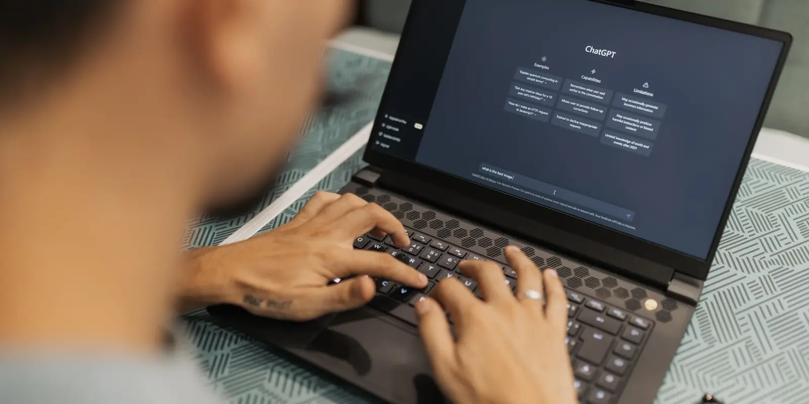 Orang ngetik pertanyaan ke asisten AI di laptop