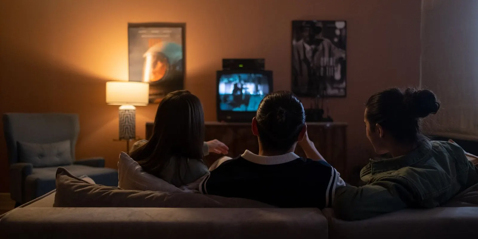 Tiga orang nonton TV di ruang tamu malam hari
