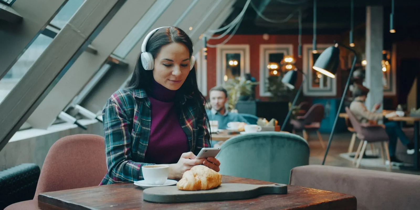 Perempuan dengerin musik pakai headphone di kafe